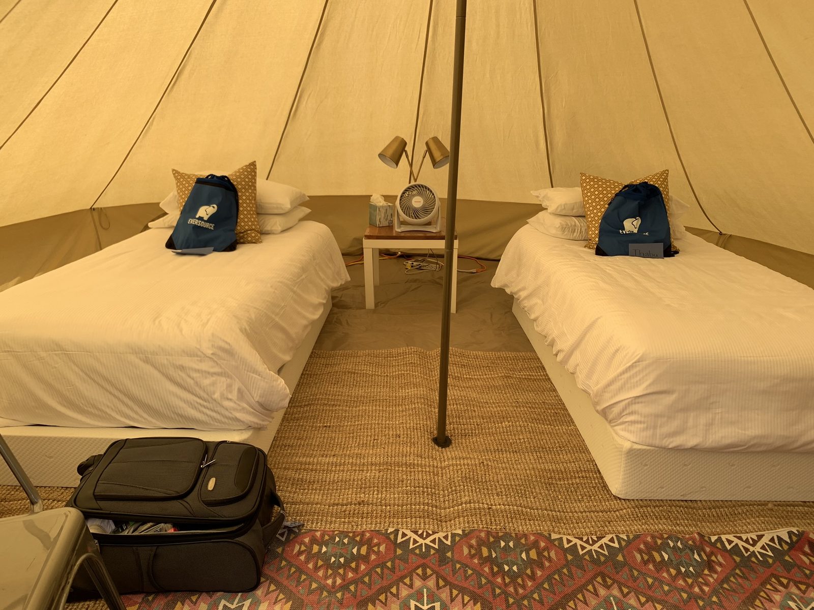 Inside a glamping bell tent with twin beds, linens, and soft lighting