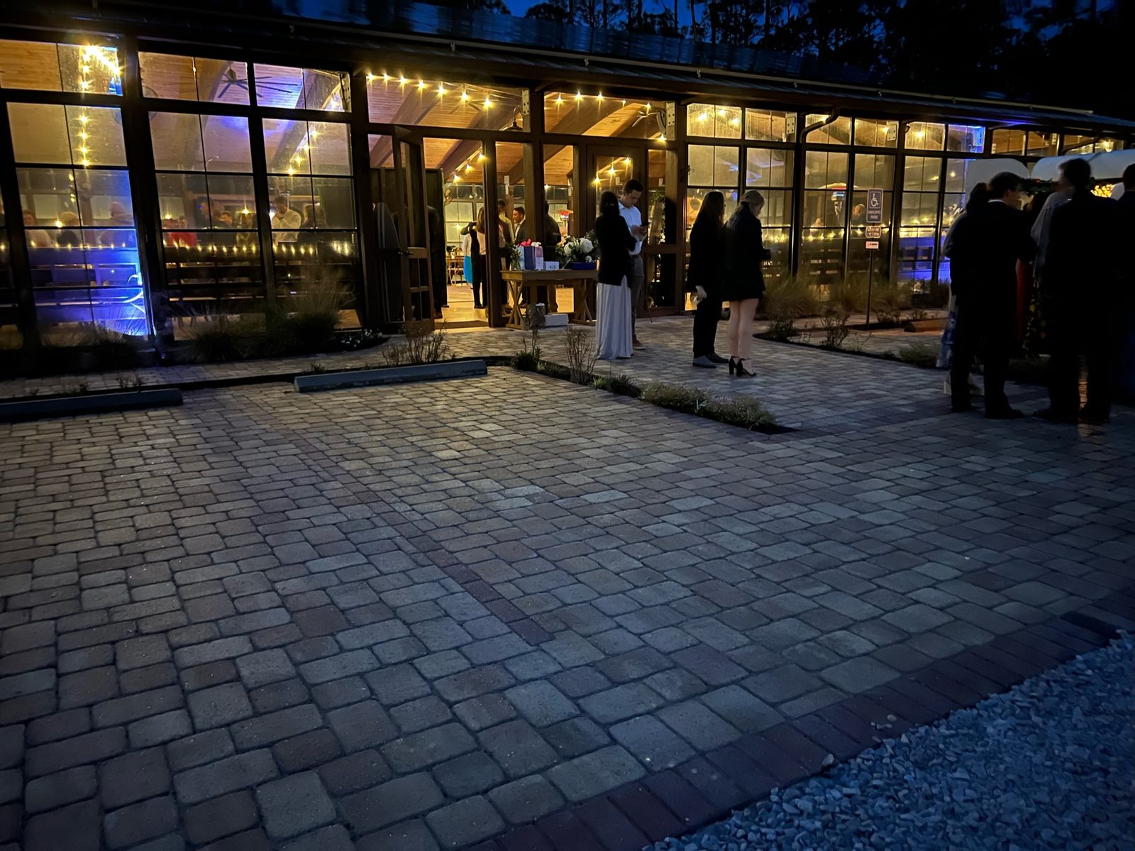Guests in evening attire arriving at the glowing pavilion entrance at dusk